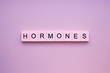 Hormones word wooden cubes on a pink background