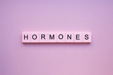 hormones word wooden cubes on a pink background