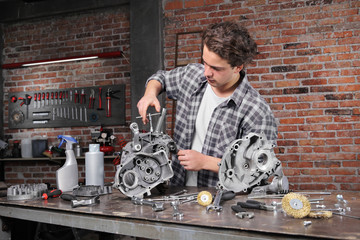 man work with the socket wrench, repair and cleaning engine parts on the workbench in home garage workshop, diy concept