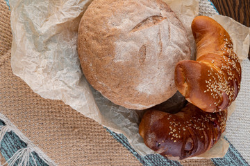 Homemade fresh round bread and two croissants with filling. Delicious homemade pastries. Close up.