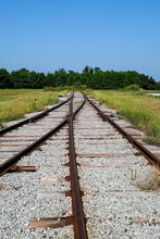 Old Rusty Railroad Tracks Crossing Into Nowhwere On Gravel Bed