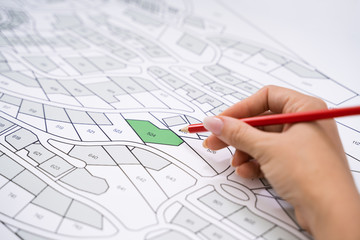 Poster - Human Hand Holding Pencil Over Cadastre Map