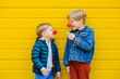 Red Nose Day Concept. Happy little brothers wearing red clown noses having fun together on sunny autmn day outdoor, yellow background.