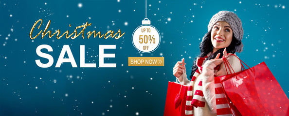 Wall Mural - Christmas sale message with young woman holding shopping bags
