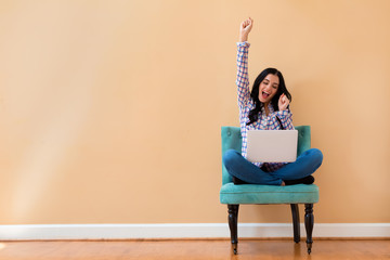 Wall Mural - Young woman with a laptop computer with successful pose sitting in a chair