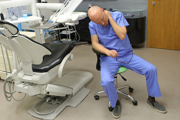 Neck pain in the dental practice.Mature dentist having short break for regeneration after long working hours in his office