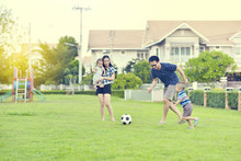 Portrait Of Asian Family Playing Football Together In Garden