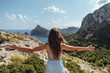 Epic shot of a woman with arms open on the edge of a rock contemplating the incredible view of Cape Formentor in Majorca, Balearic Islands, Spain. Vertical photo.