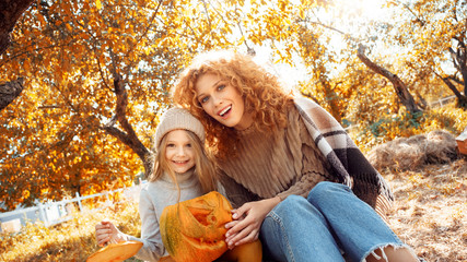 Young adult mother and daughter looking at carved pumpkin with smoke