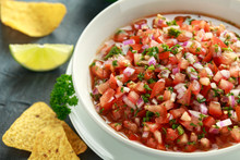Mexican Tomato Salsa In White Bowl With Lime, Red Onion, Jalapeno Pepper, Parsley And Tortilla Chips