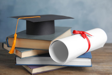 Wall Mural - Graduation hat, books and student's diploma on wooden table