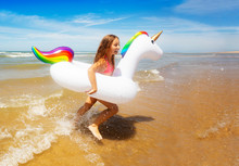 Happy Girl Run Over Waves In Inflatable Unicorn