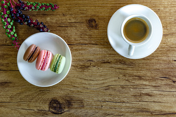 colored macarons and a cup of coffee on a wooden rustic table near 