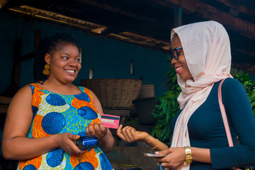 market woman receiving credit card from her customer to pay her bills