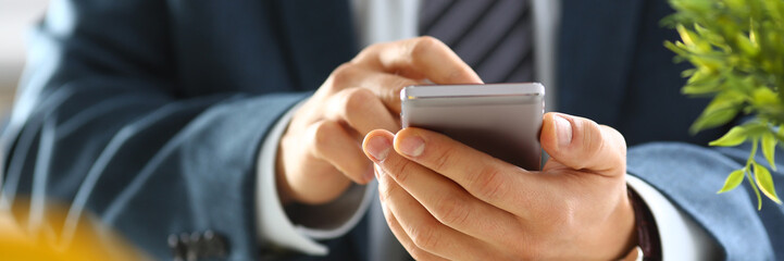 male arm in suit hold phone and silver pen