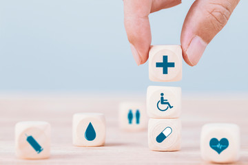 Hand chooses a emoticon icons healthcare medical symbol on wooden block , Healthcare and medical Insurance concept