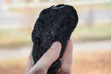 A man holds in his hand a Slice of fresh bread black ciabatta with activated carbon, crispy crust and porous flesh. For a traditional Italian or French Breakfast. Close-up view.