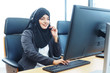 © TS.PHOTOS - Beautiful active and smart Muslim call center woman sitting in front of her computer talking to customer on the phone