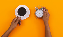 Black Women's Hands Holding Alarm Clock And Coffee Cup