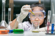 © kwanchaichaiudom - Little girl wearing safty goggle making experiment