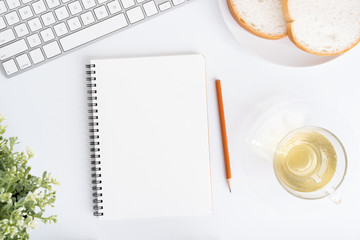 Wall Mural - top view of office table. on desk have notebook, teacup, bread, laptop, and pencil on white ground