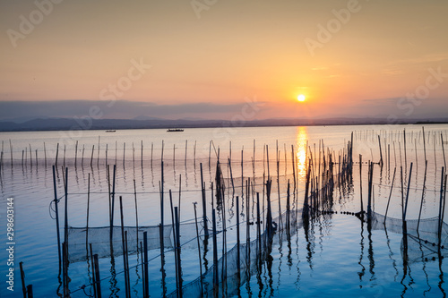 atardecer-en-el-lago-la-albufera-con-barcas-montanas-y-puesta-de-sol