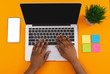 © Prostock-studio - Black female hands typing on laptop over orange background