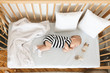 © Prostock-studio - Cute infant baby napping on his side in wooden cot