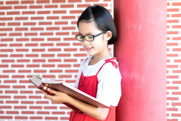 Poster - happy child little girl with glasses reading a books