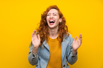 Redhead woman over isolated yellow background laughing