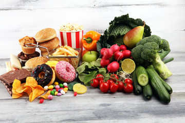 Wall Mural - healthy or unhealthy food. Concept photo of healthy and unhealthy food. Fruits and vegetables vs donuts and fast food