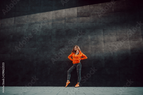 Fotomural Full length of attractive fit caucasian woman in sportswear posing while standing against black wall