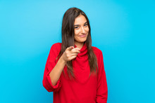 Young Woman With Red Sweater Over Isolated Blue Background Points Finger At You