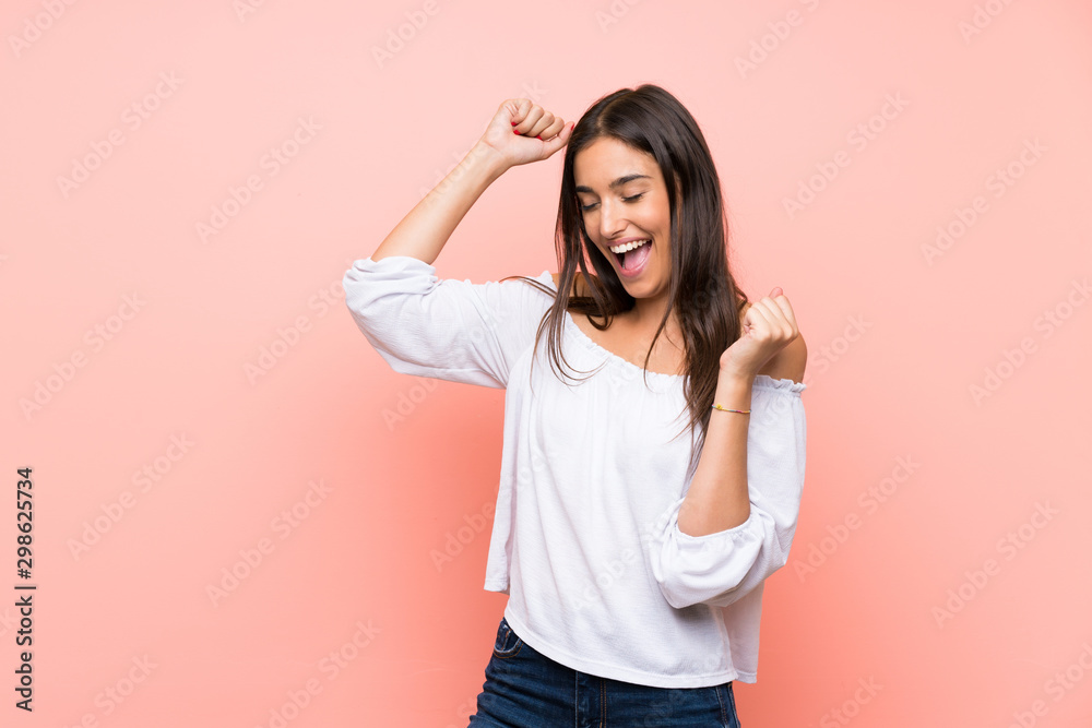 Young woman over isolated pink background celebrating a victory - obrazy, fototapety, plakaty 