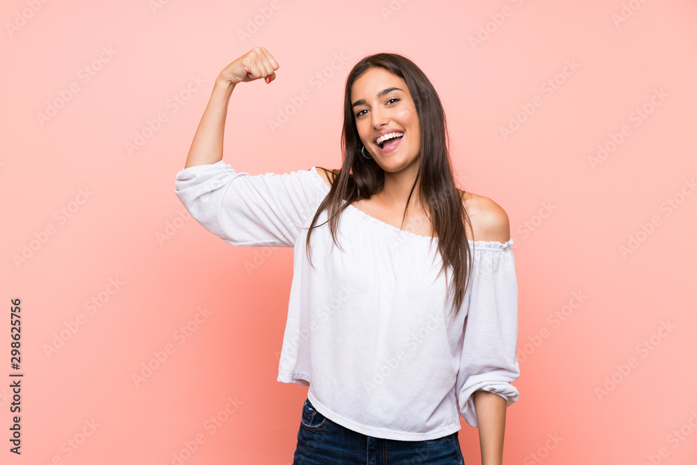 Young woman over isolated pink background doing strong gesture - obrazy, fototapety, plakaty 