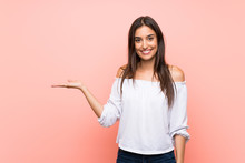 Young Woman Over Isolated Pink Background Holding Copyspace Imaginary On The Palm To Insert An Ad
