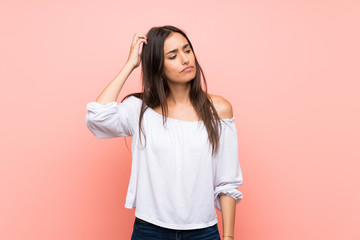 Young woman over isolated pink background having doubts while scratching head