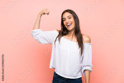 Fotomural Young woman over isolated pink background doing strong gesture