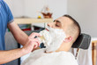 © Anna - Hairdresser shaves a beard to a man with a razor in the barbershop