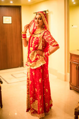 Beautiful female model in traditional indian bridal costume with heavy makeup and gold jewelery, indian bride portrait