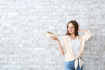 Wall Mural - Beautiful young woman with hat against brick wall