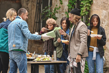 Volunteers Giving Food To Homeless People Outdoors