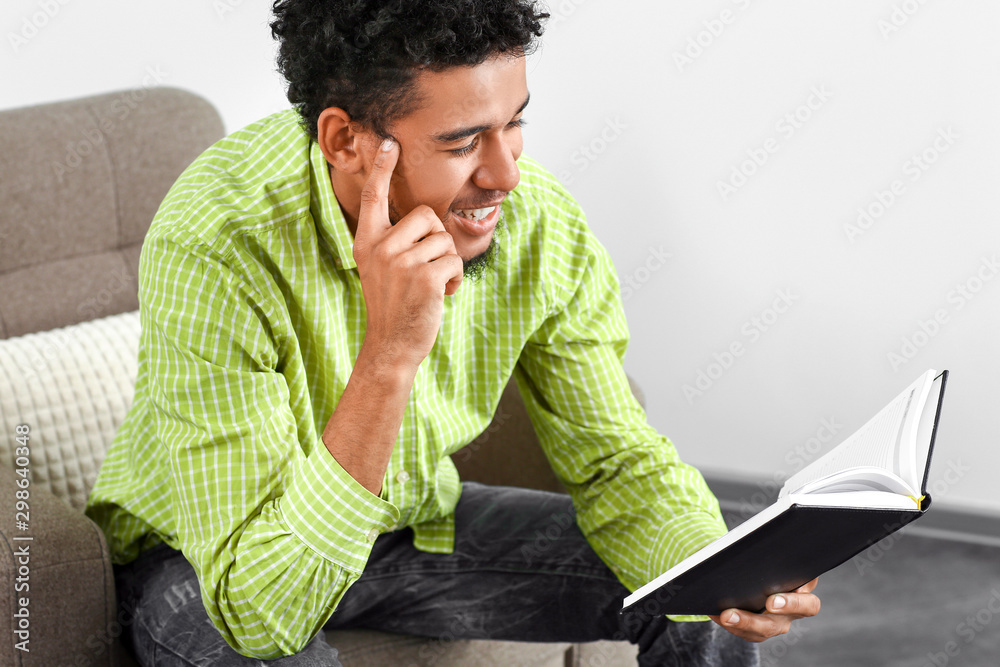 Happy African-American man reading book at home