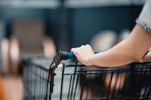 Close Up Hand Of Female Shopper With Trolley, Shopping Cart At Supermarket.