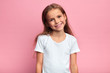 cheerful blonde girl in white T-shirt looking at the camera with positive expression. close up portrait, isolated pink background, studio shot
