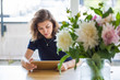 © papa - A young woman uses a digital tablet while sitting at a table.