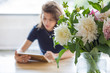 © papa - A young woman uses a digital tablet while sitting at a table.