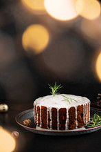 Traditional Christmas Cake With Fruits And Nuts On A Dark Table And Black Background. Dessert For The Winter Holidays. Christmas Decorations And Lights. Copyspace. Vertical. Bokeh