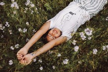 Model Laying Down In A Daisy Field With Her Eyes Closed