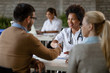 © Drazen - Happy African American doctor shaking hands with a couple at clinic.
